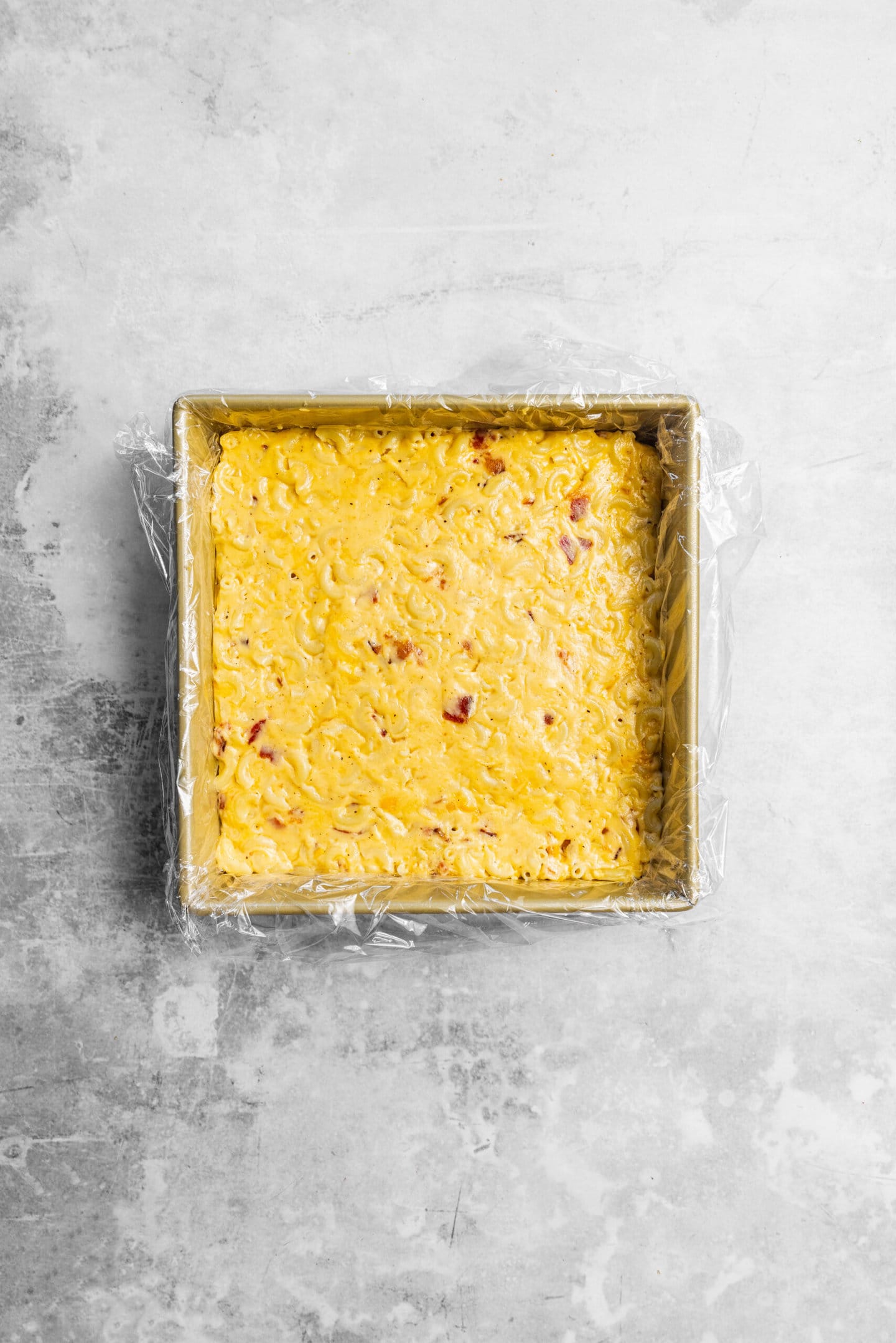 bacon mac and cheese smoothed into an even layer in baking pan.
