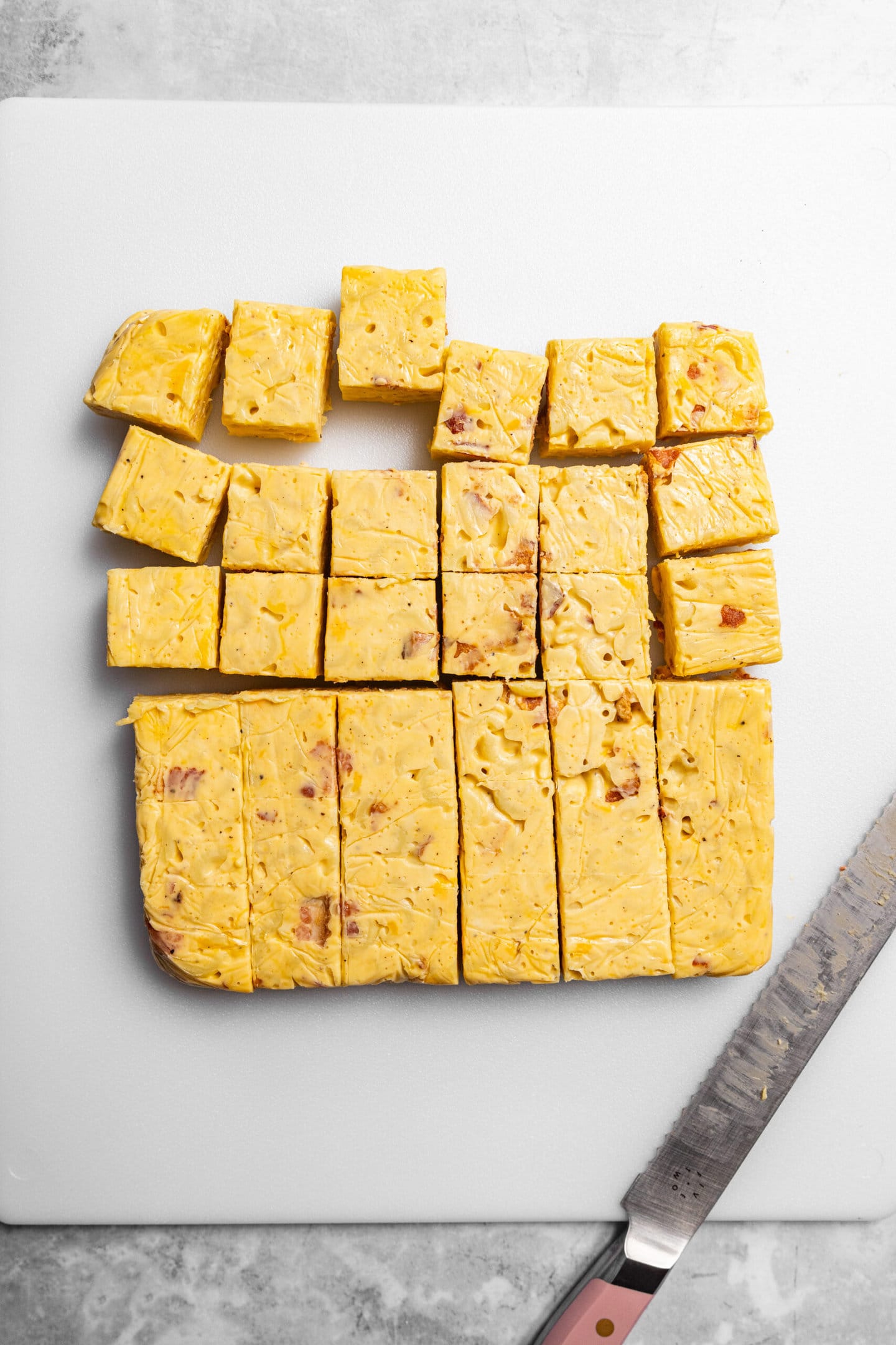 Bacon mac and cheese being sliced into bite sized pieces.