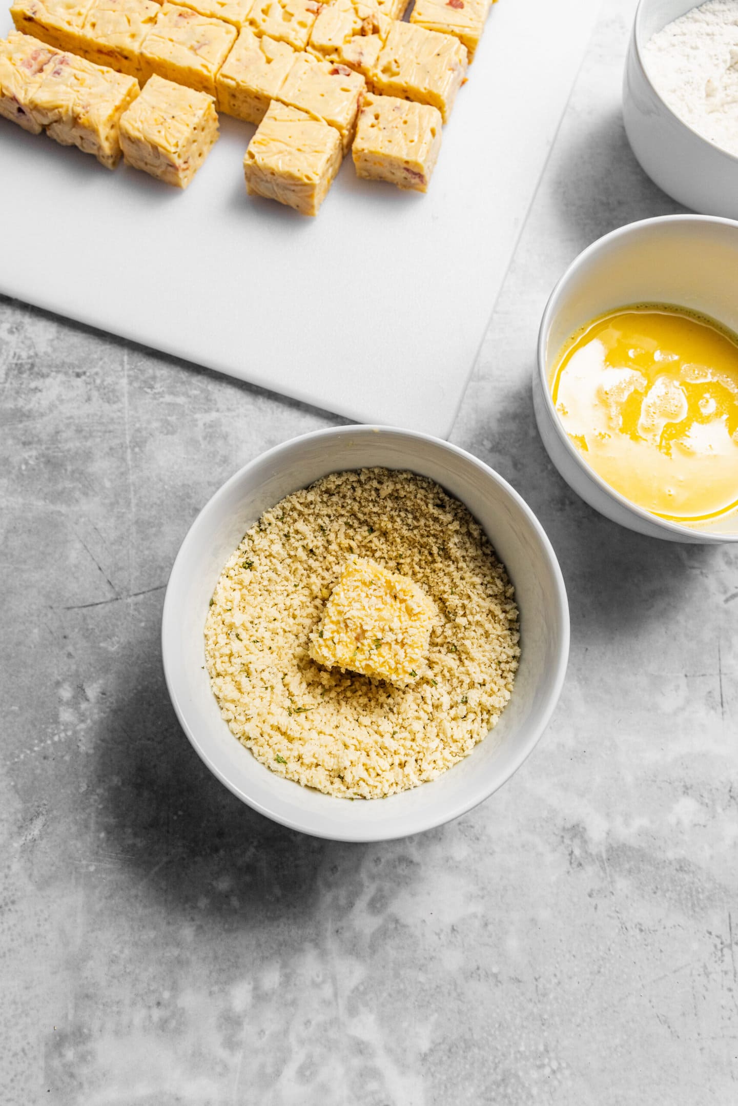 Mac and cheese bites being breaded.