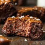 A close up of a fudge brownie with flaky sea salt on top and a bite missing