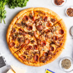 Sliced Meat Lover's Pizza surrounded by fresh ingredients