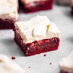 Slices of red velvet brownies with cream cheese frosting swirled on top
