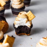S'mores cupcake with a bite missing surrounded by other cupcakes.