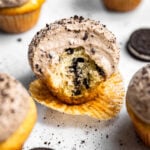 Oreo cupcake topped with Oreo whipped cream frosting with a bite missing.