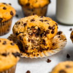Close up of Small Batch Chocolate Chip Muffin with a bite taken out of it next to a glass of milk
