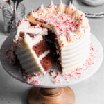 Sliced chocolate peppermint layer cake on top of cake stand showing moist chocolate interior.