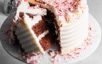 Sliced chocolate peppermint layer cake on top of cake stand showing moist chocolate interior.