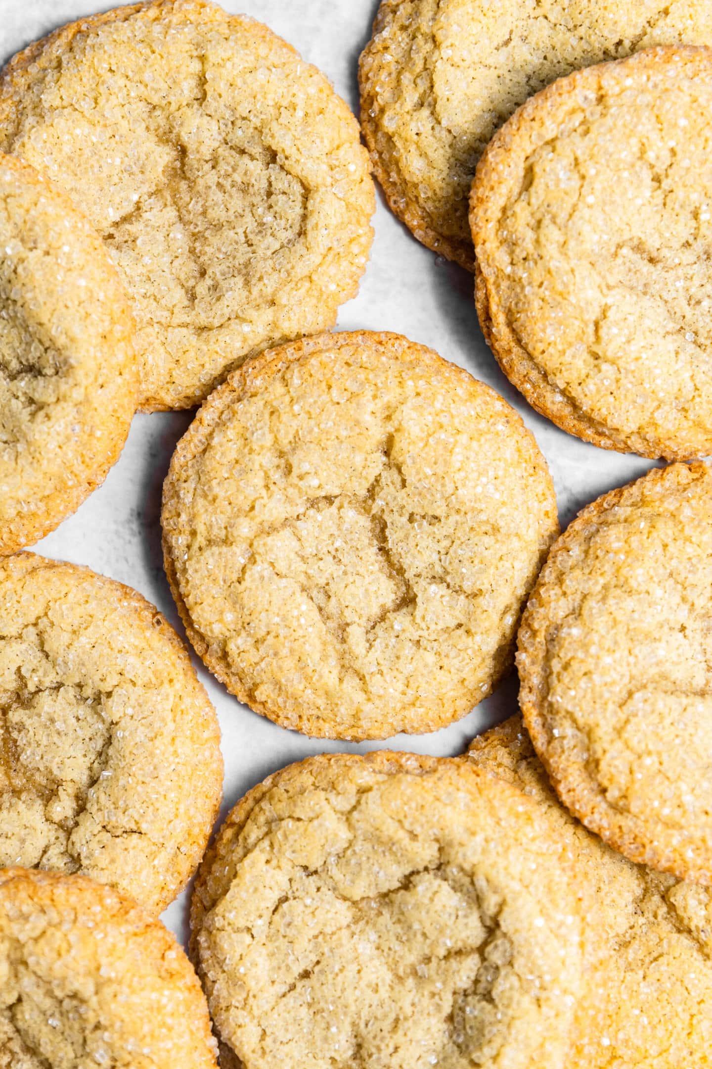 Freshly baked drop style sugar cookies spread on a marble countertop.