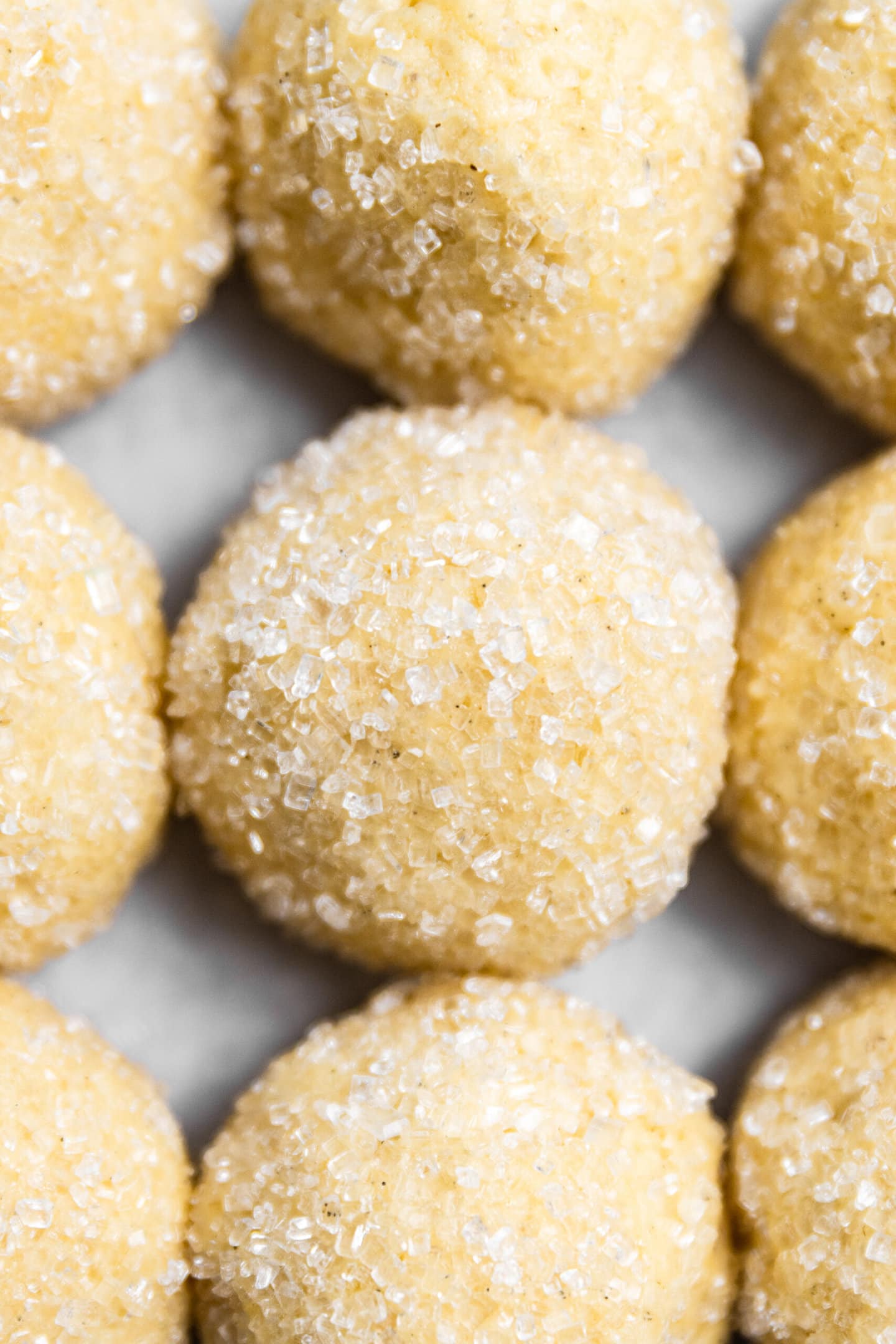Close up of sugar cookie dough balls rolled in sparkling sugar.