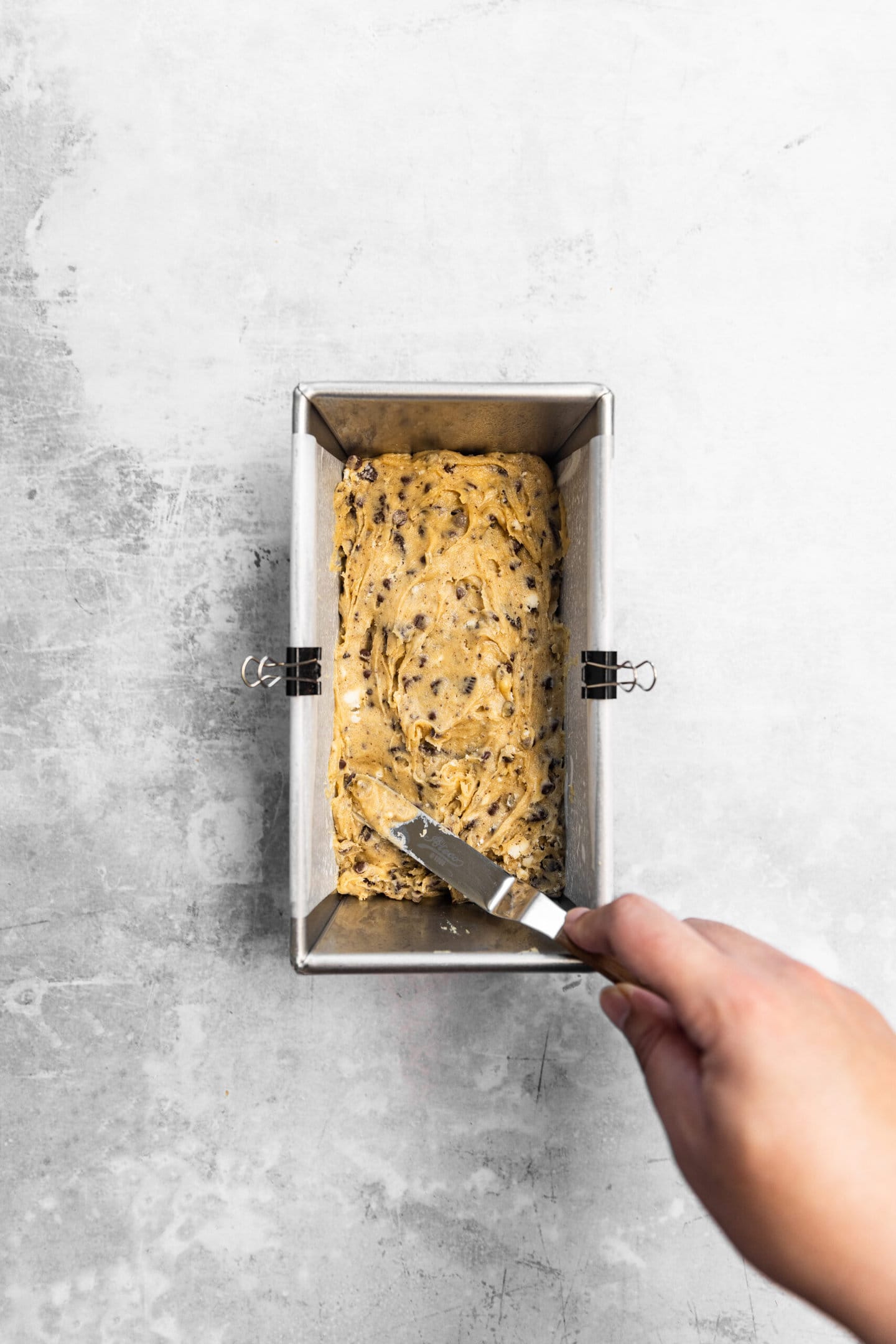 Oreo blondie batter being spread into prepared baking pan.