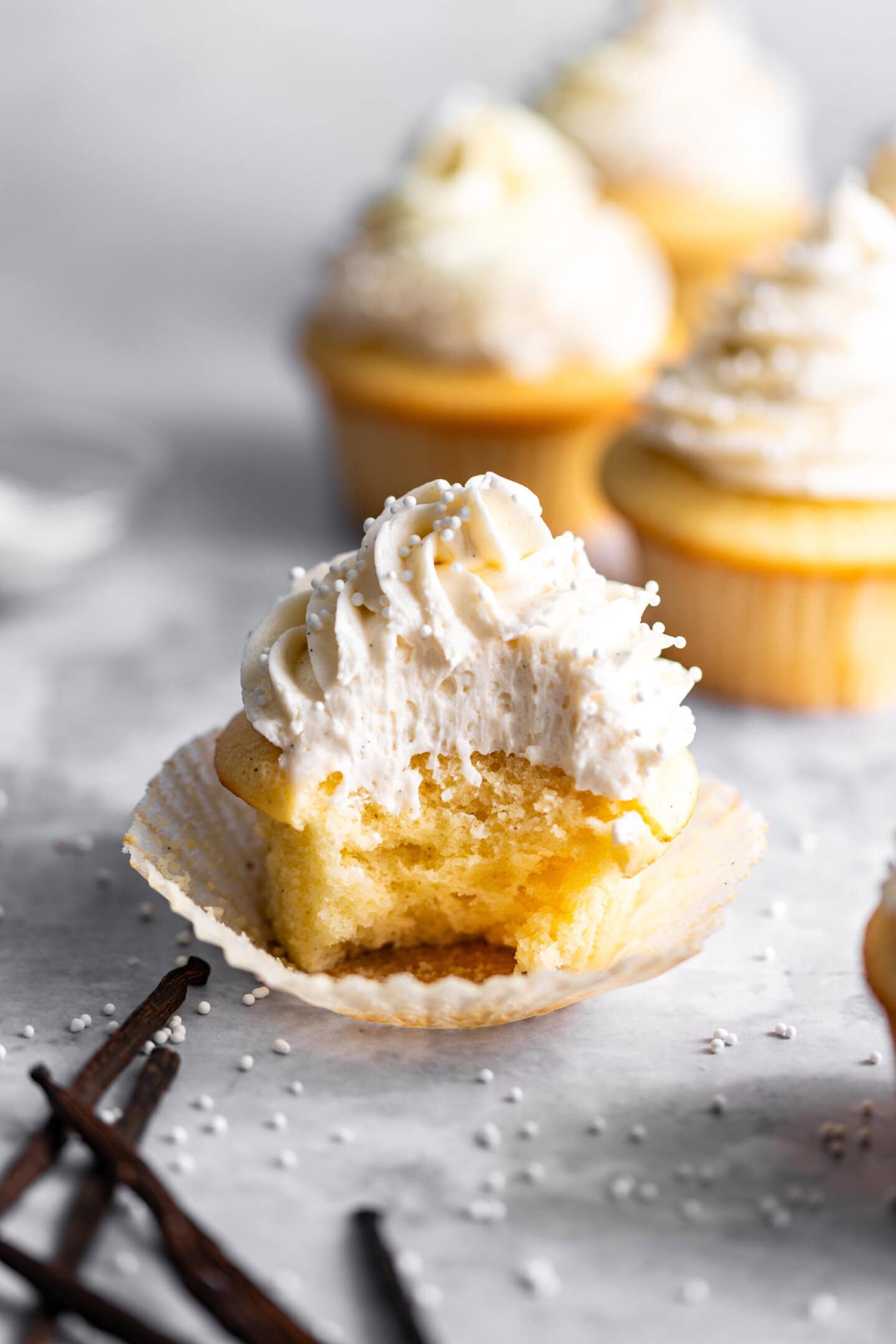 Close up of vanilla cupcake with double vanilla buttercream on top with a bite missing
