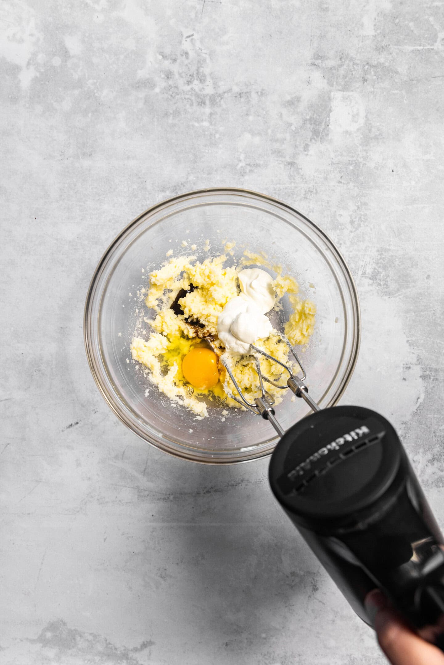 Egg, sour cream, and vanilla bean paste being beaten into the butter and sugar mixture