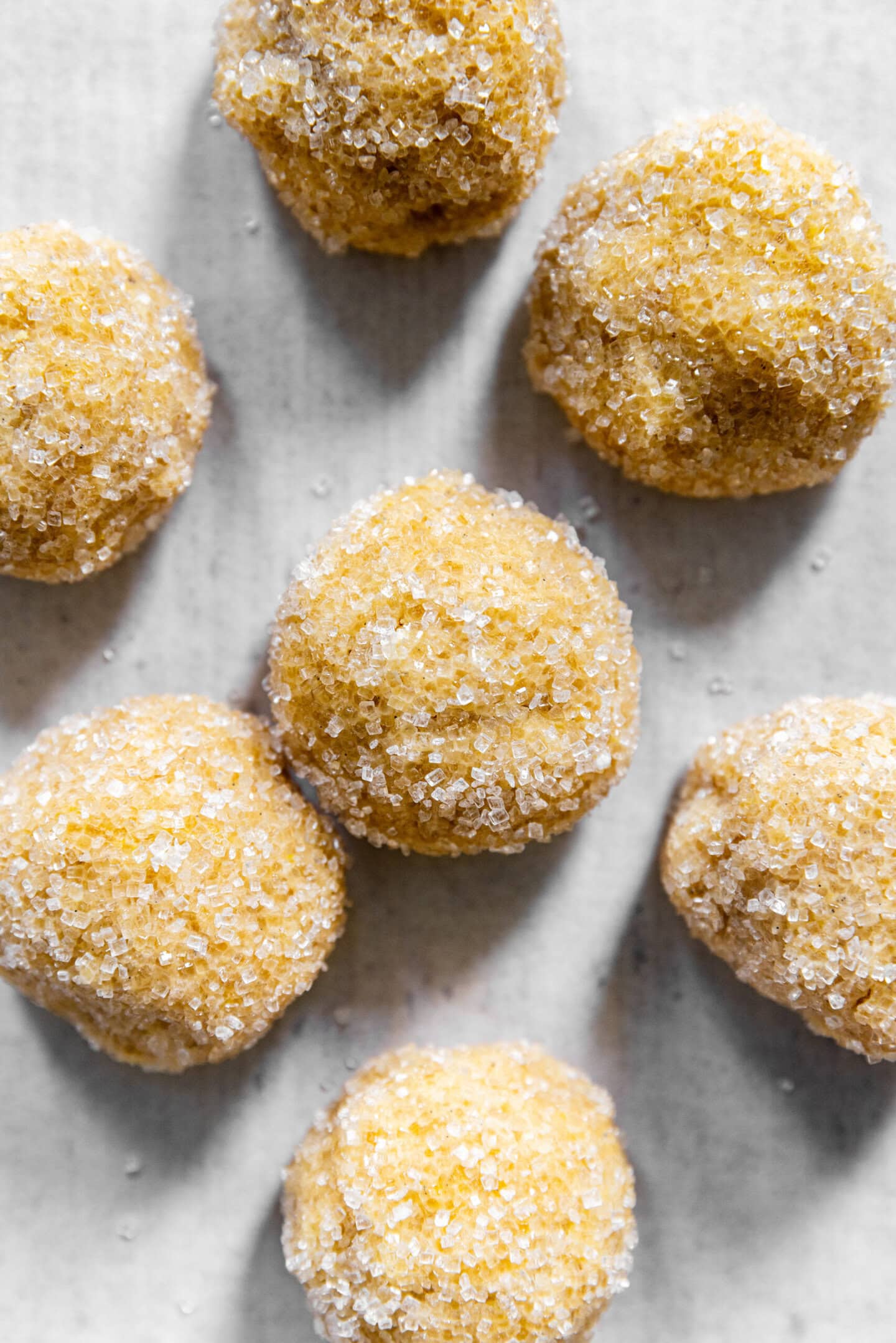 Lemon sugar cookie dough rolled in sparkling sugar on a sheet pan