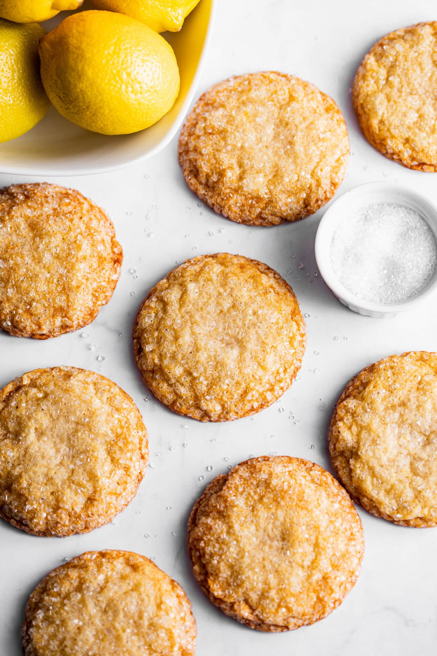 Freshly baked lemon sugar cookies next to a bowl of lemons