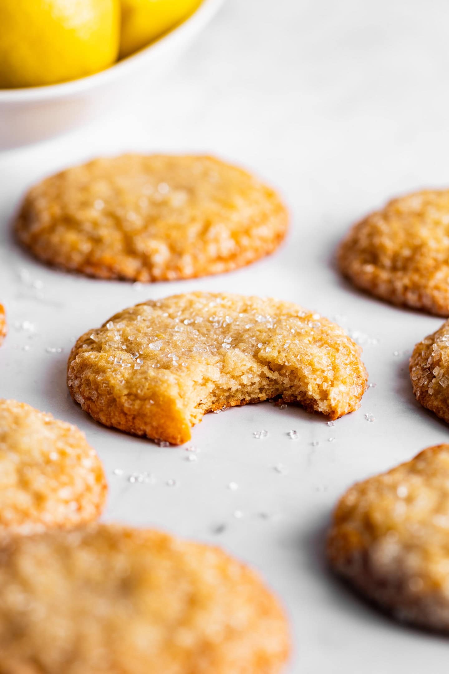 Close up of lemon sugar cookie with a bite missing showing off soft and chewy texture