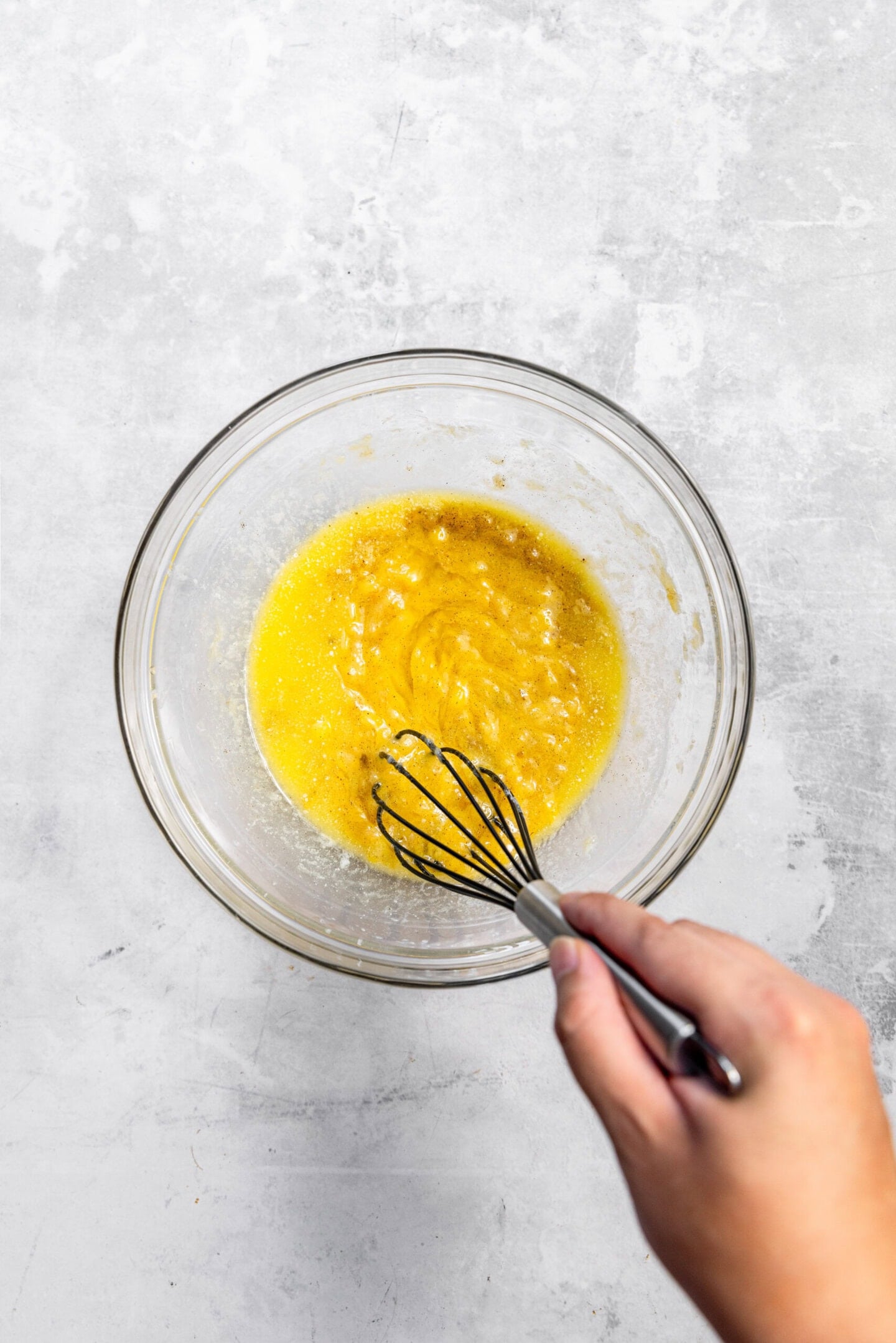 Melted butter and one egg being whisked into the mashed bananas