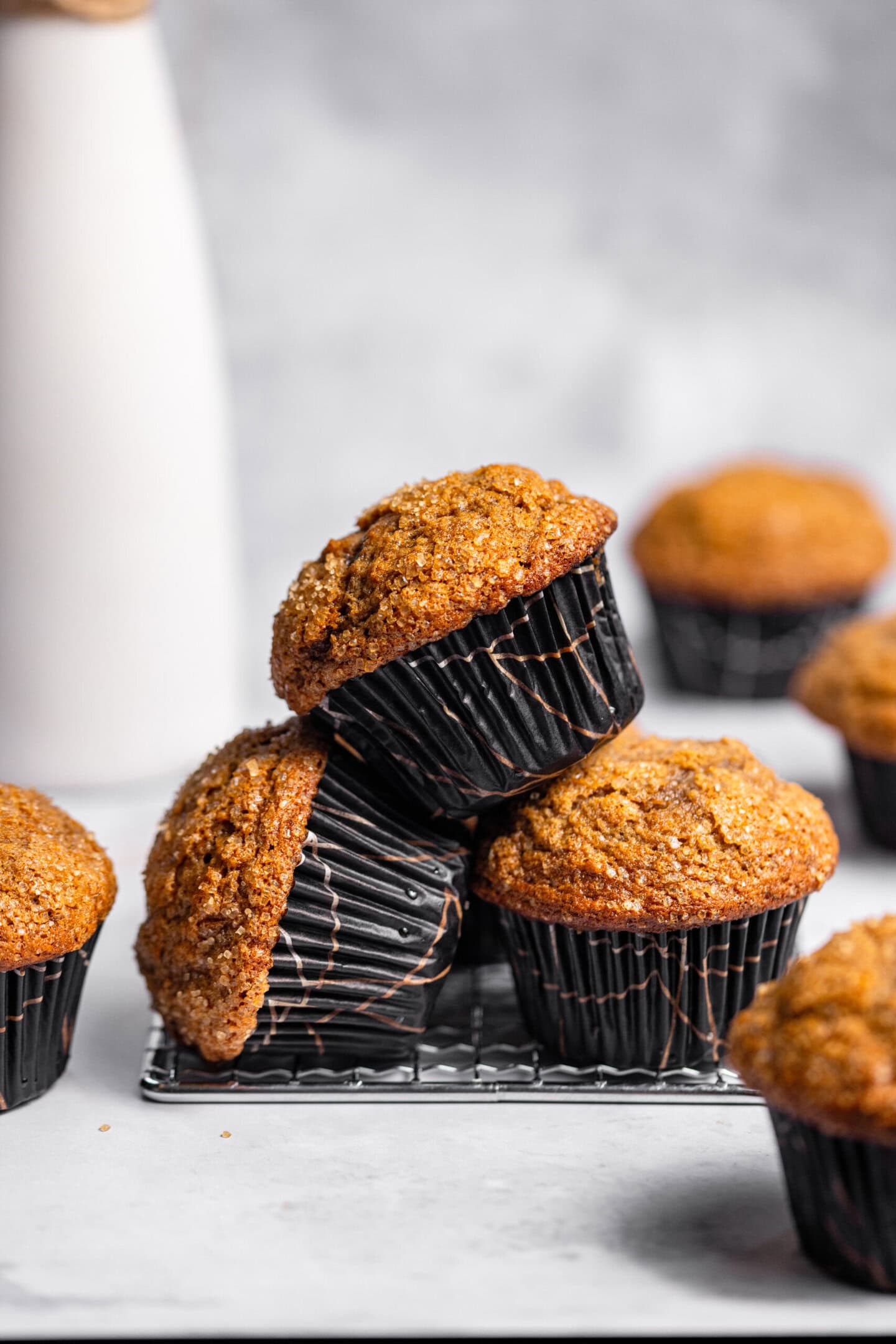 A stack of small batch banana muffins on top of and around a cooling rack.