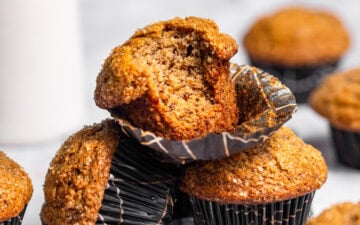 A stack of banana muffins with a bite missing from the top one.