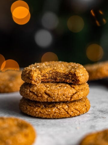 gingerbread molasses cookies stacked on top of each other with a bite missing out of one.