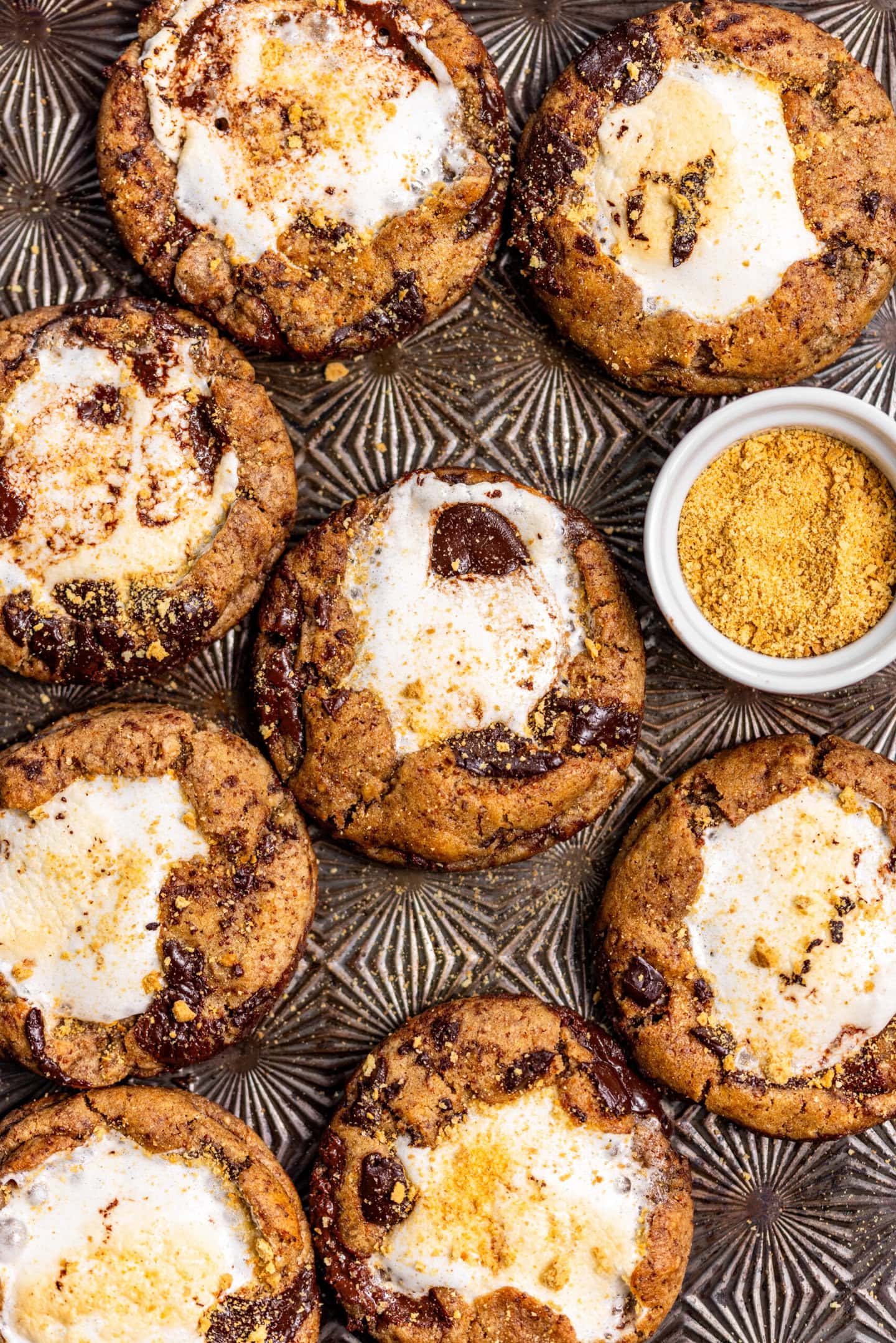 Freshly baked s'mores chocolate chip cookies on top of a baking sheet.