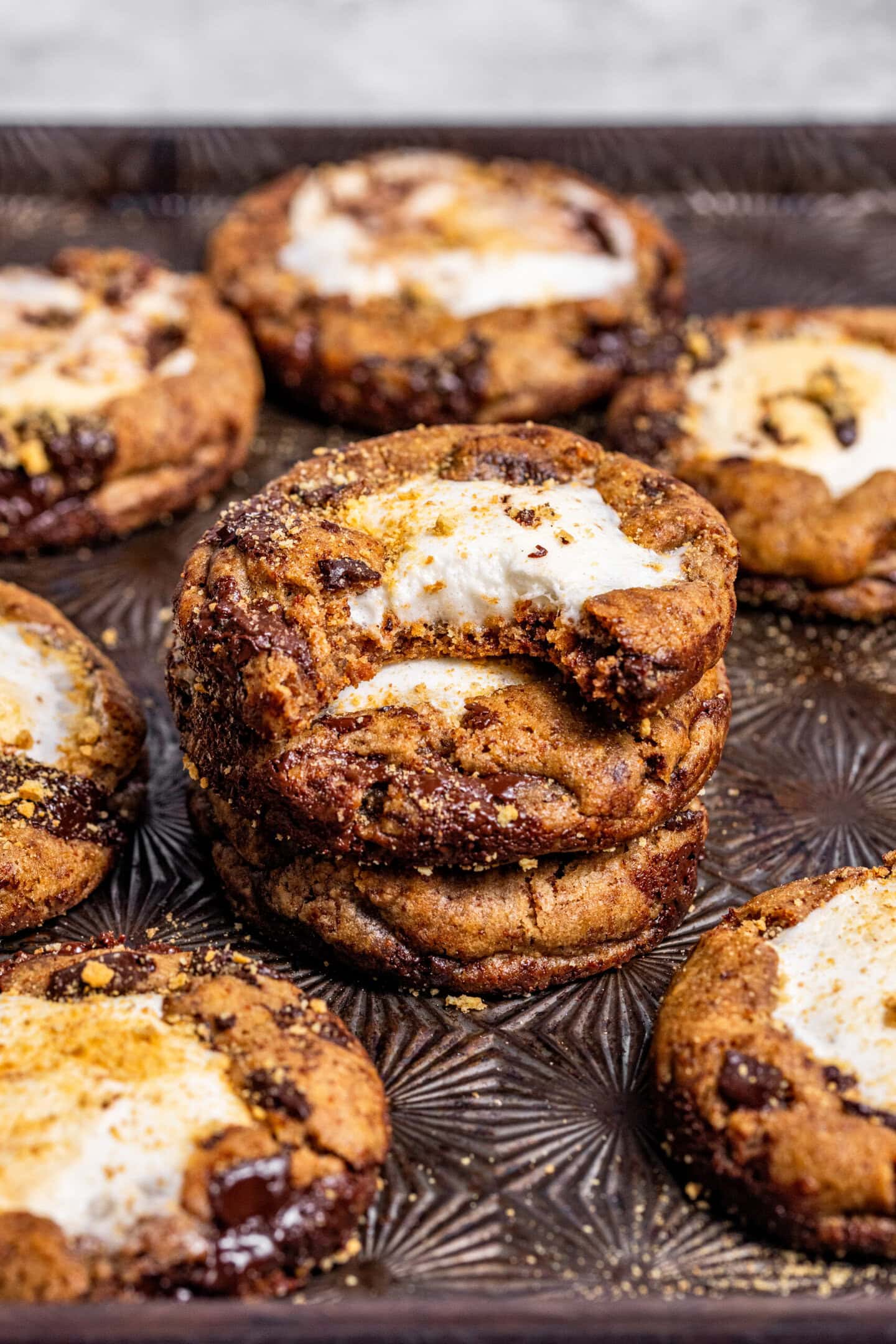 S'mores chocolate chip cookies stacked on top of each other with a bite missing from the top cookie.