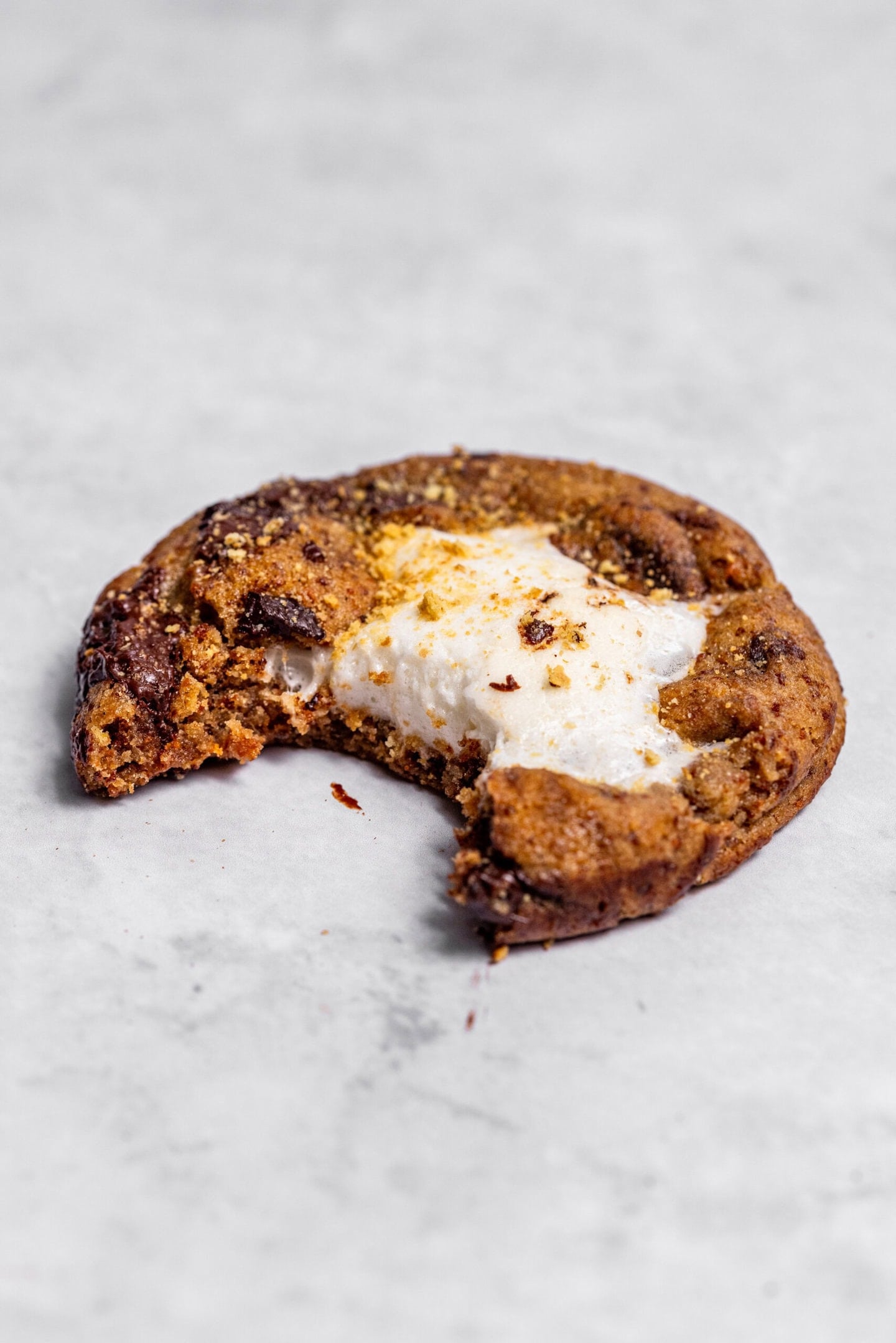 Close up of a s'mores cookie with marshmallow filling with a bite missing.