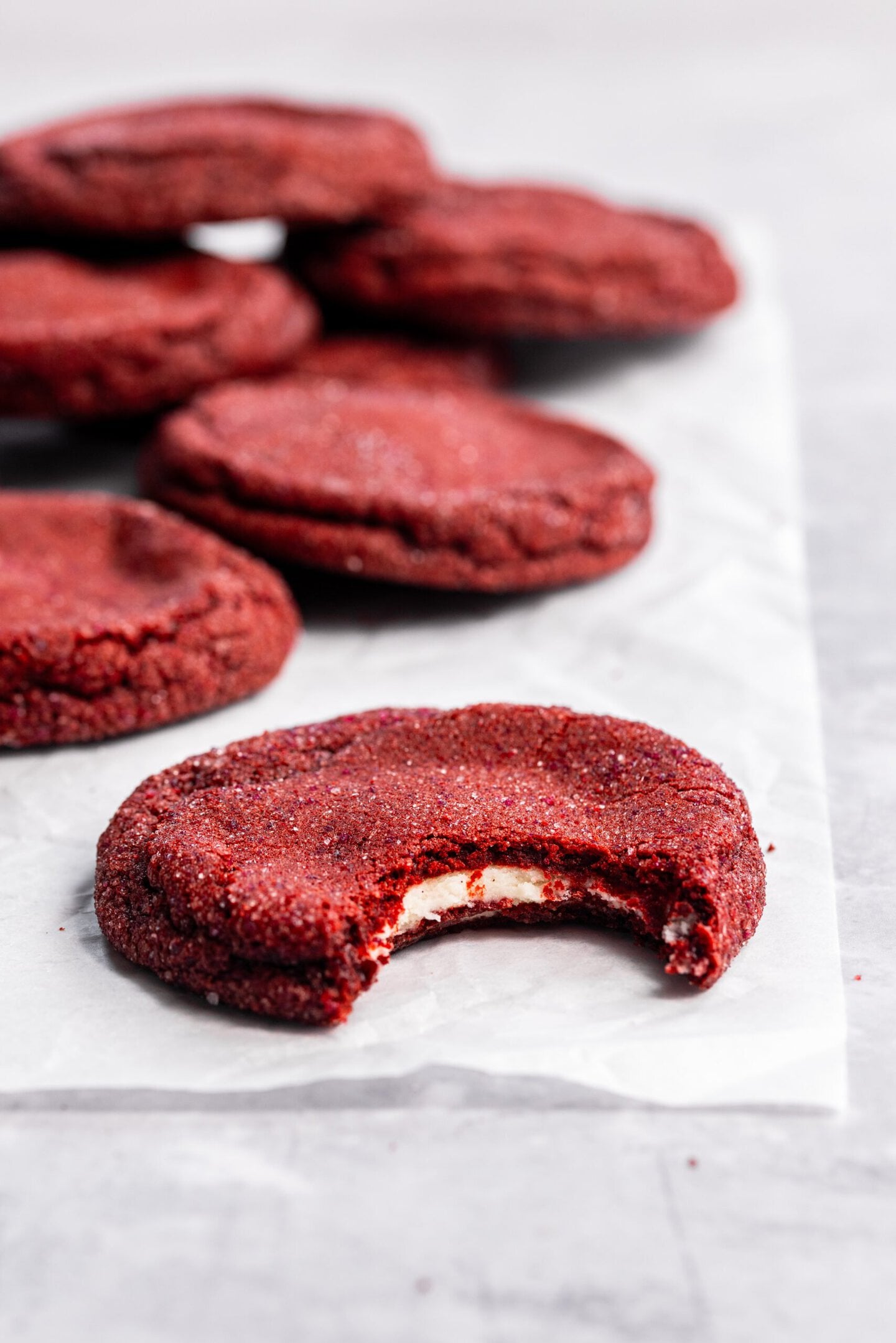 Close up of a bite missing from a red velvet cookie showing off the cream cheese filling hidden inside.