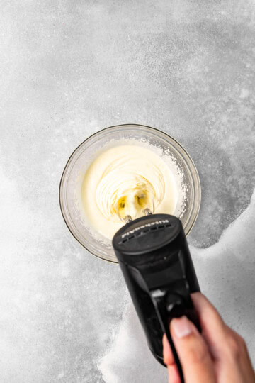 Eggs and sugar being whipped together with a hand mixer on high speed.