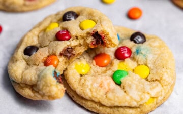 Close up of freshly baked M&M cookies with a bite missing from one showing off soft, chewy interior.