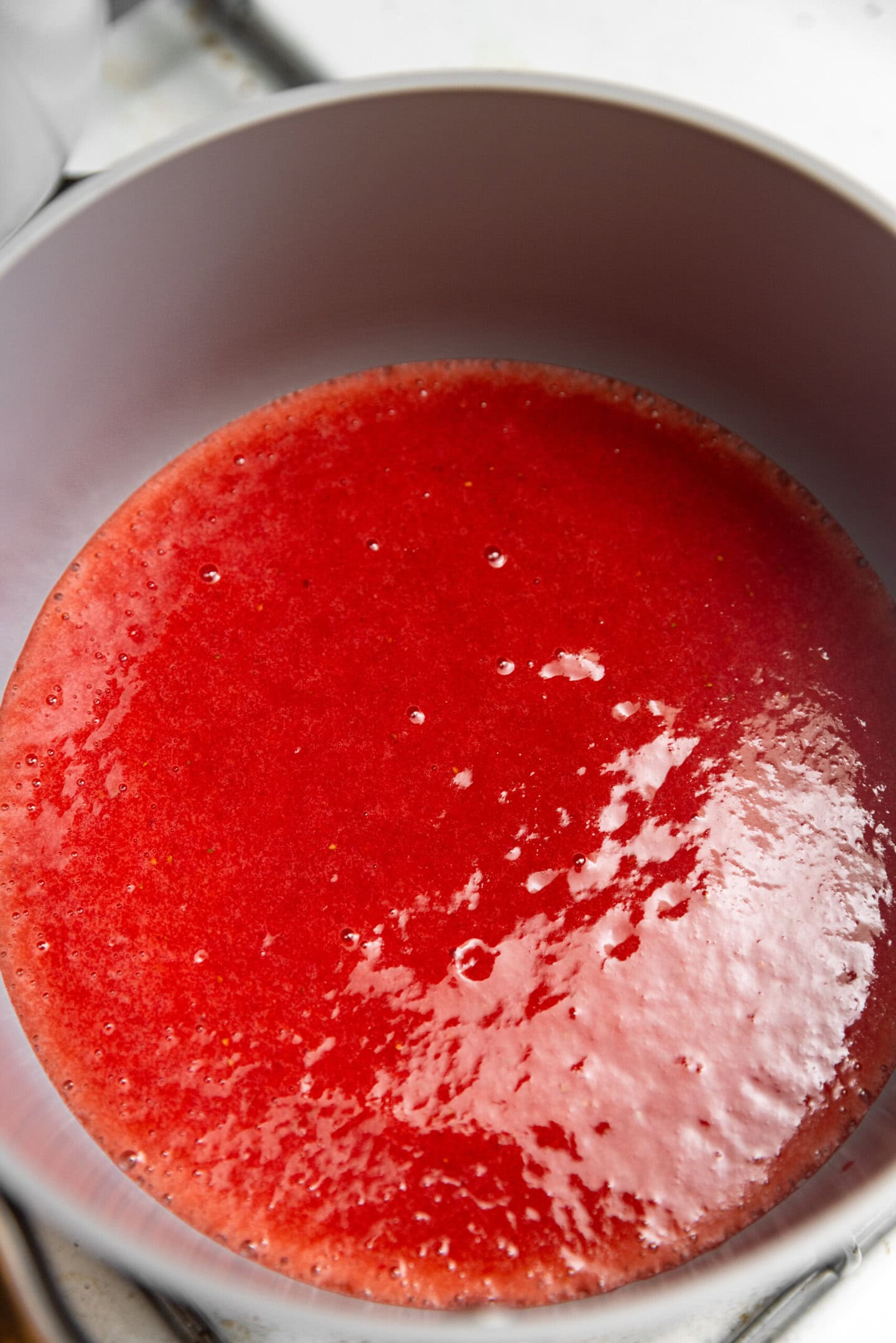 Pureed strawberries being cooked in a saucepan over heat.