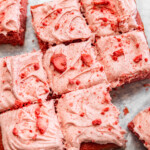Sliced strawberry snack cake with strawberry cream cheese frosting on top.