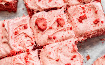 Sliced strawberry snack cake with strawberry cream cheese frosting on top.
