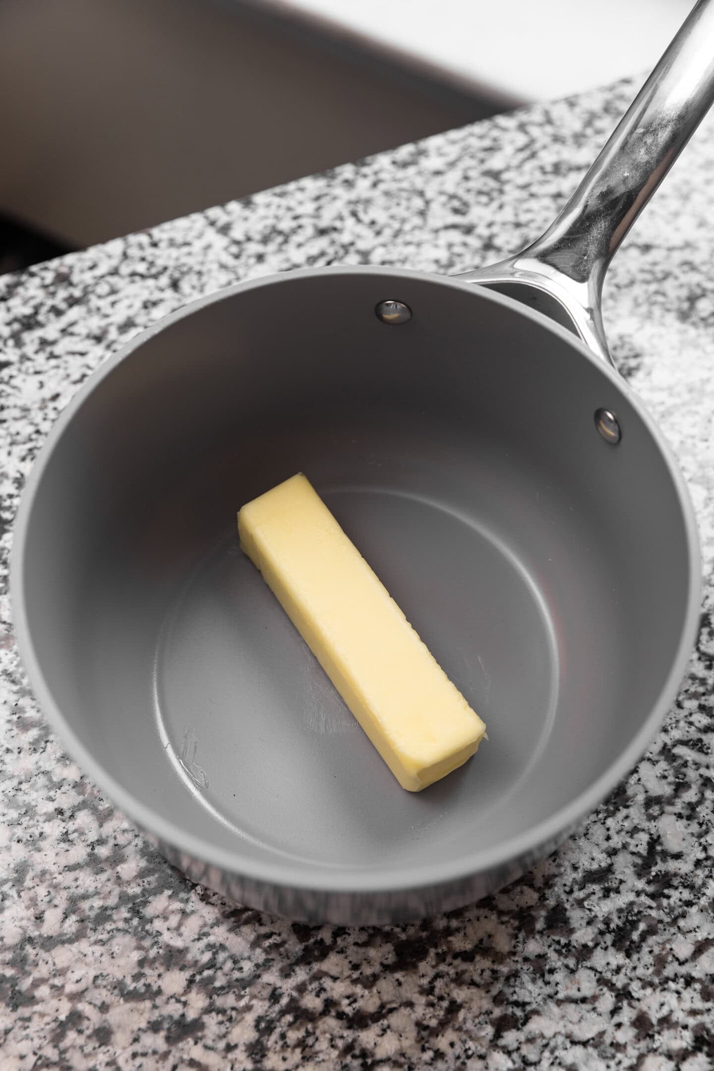 A stick of butter being melted down in a saucepan.