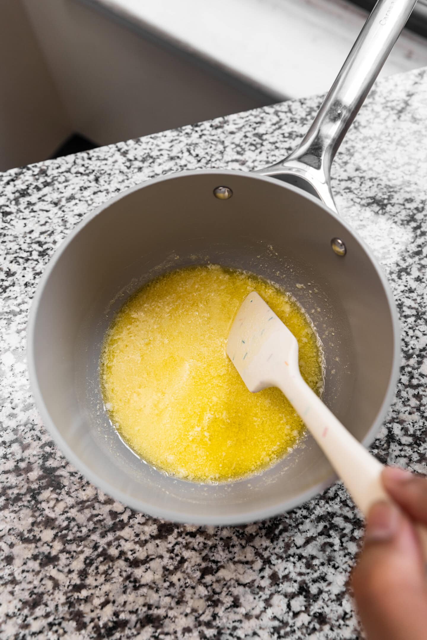 Dry milk powder being stirred into melted butter.