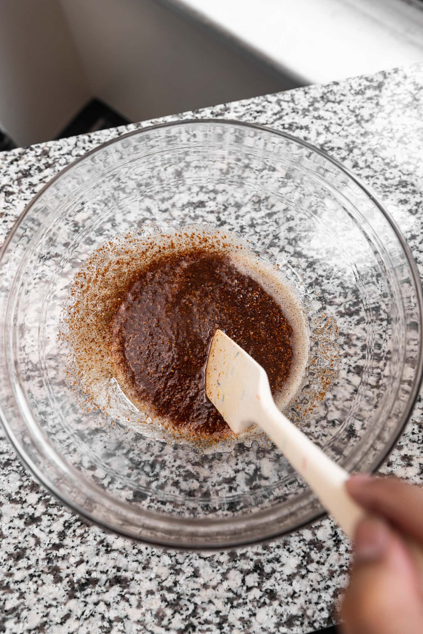 Brown butter being stirred inside of a glass mixing bowl.