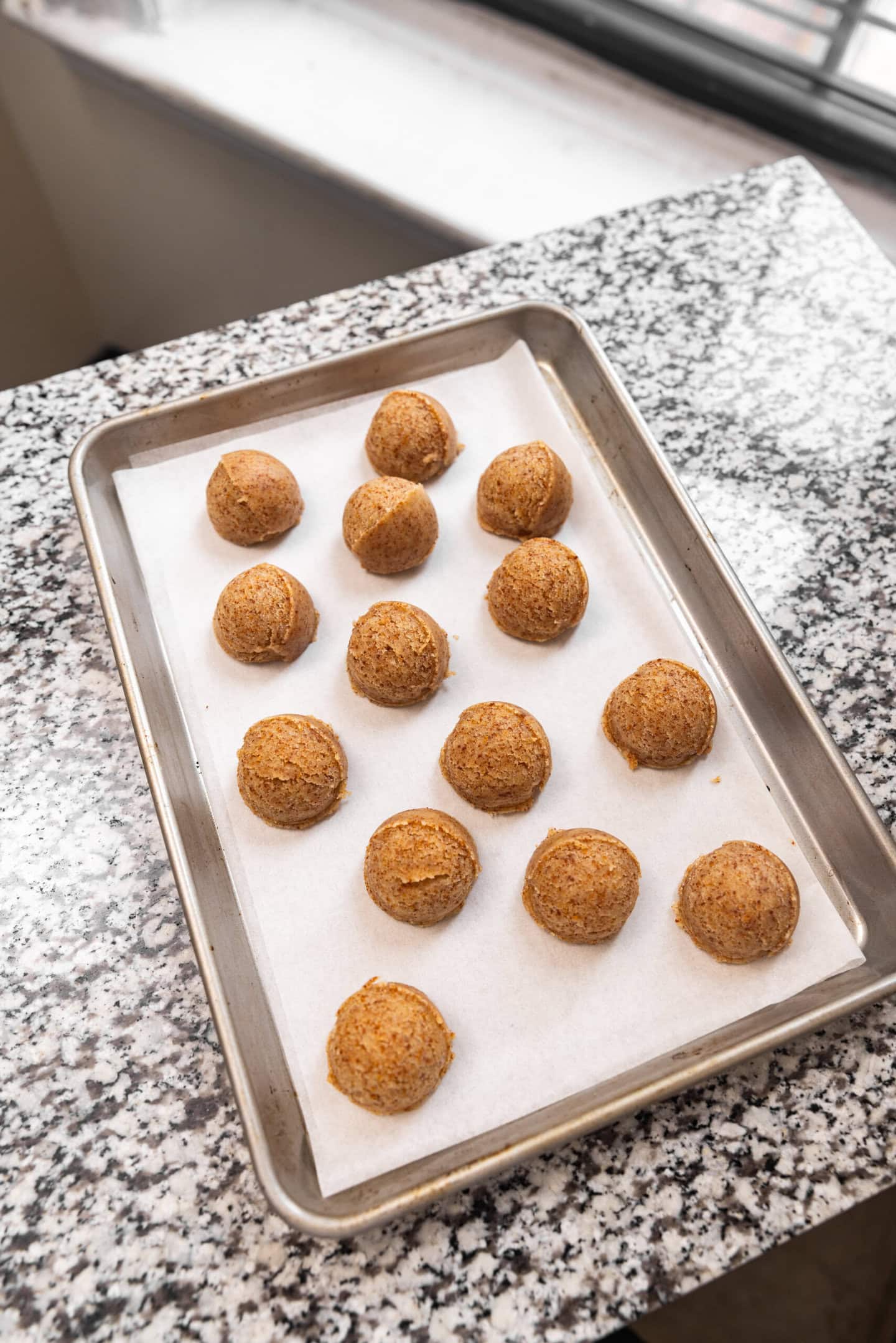 Brown butter sugar cookie dough balls spaced out on a baking sheet.