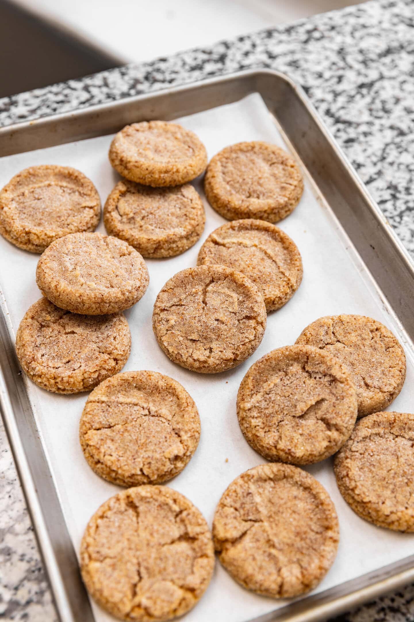 Freshly baked extra-toasty brown butter sugar cookies (with milk powder) sitting on a baking tray on top of a kitchen counter.