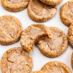Brown butter sugar cookies on top of a baking sheet with a bite missing out of one showing off chewy texture.