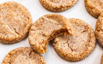 Brown butter sugar cookies on top of a baking sheet with a bite missing out of one showing off chewy texture.