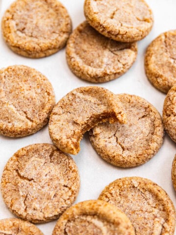 Brown butter sugar cookies on top of a baking sheet with a bite missing out of one showing off chewy texture.